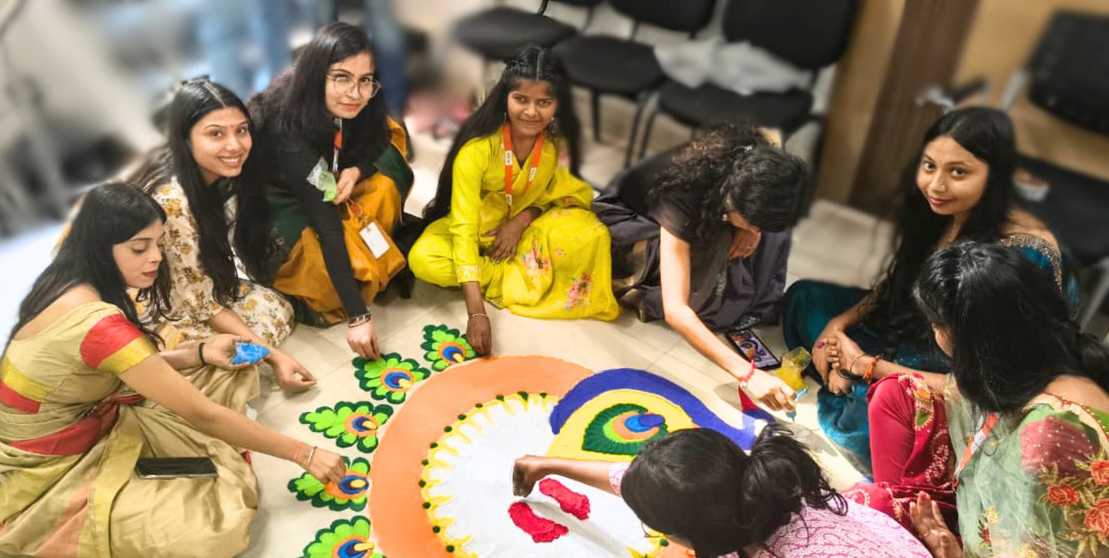 Colleagues creating a colourful rangoli on the office floor